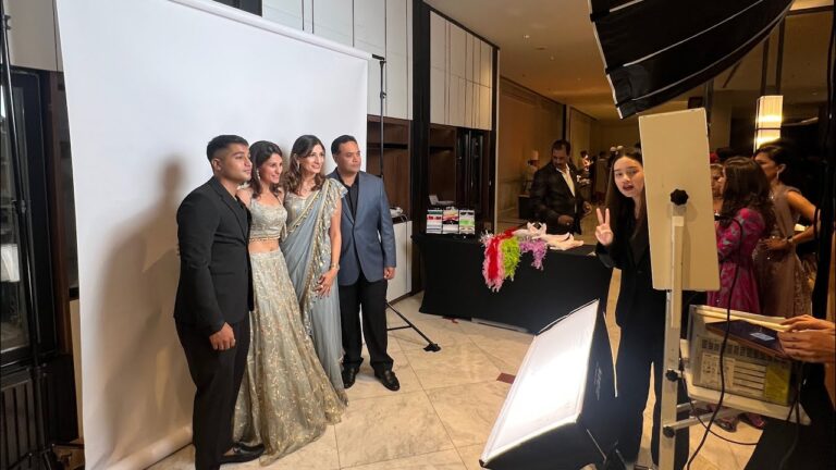 คู่บ่าวสาวและแขกโพสท่าถ่ายภาพที่โฟโต้บูธพร้อมไฟสตูดิโอในงานแต่งที่โรงแรม